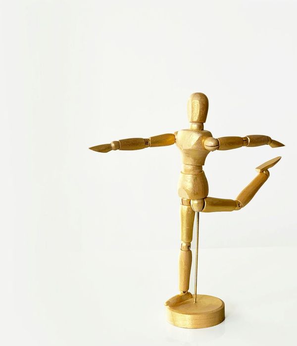 Person holding a balancing yoga pose against a minimal background.